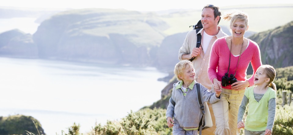 A family is walking on a hill near the ocean.