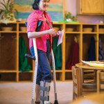 A woman standing in a classroom with Mobilegs ergonomic crutches.